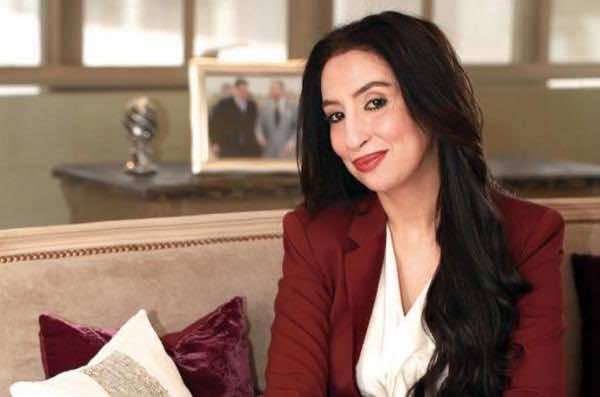 Salwa Idrissi Akhannouch seated in a salon interior, wearing a red jacket.