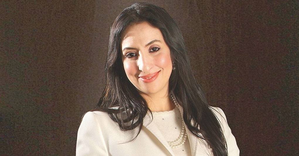 Corporate portrait of Salwa Idrissi Akhannouch in a cream jacket against a dark backdrop.